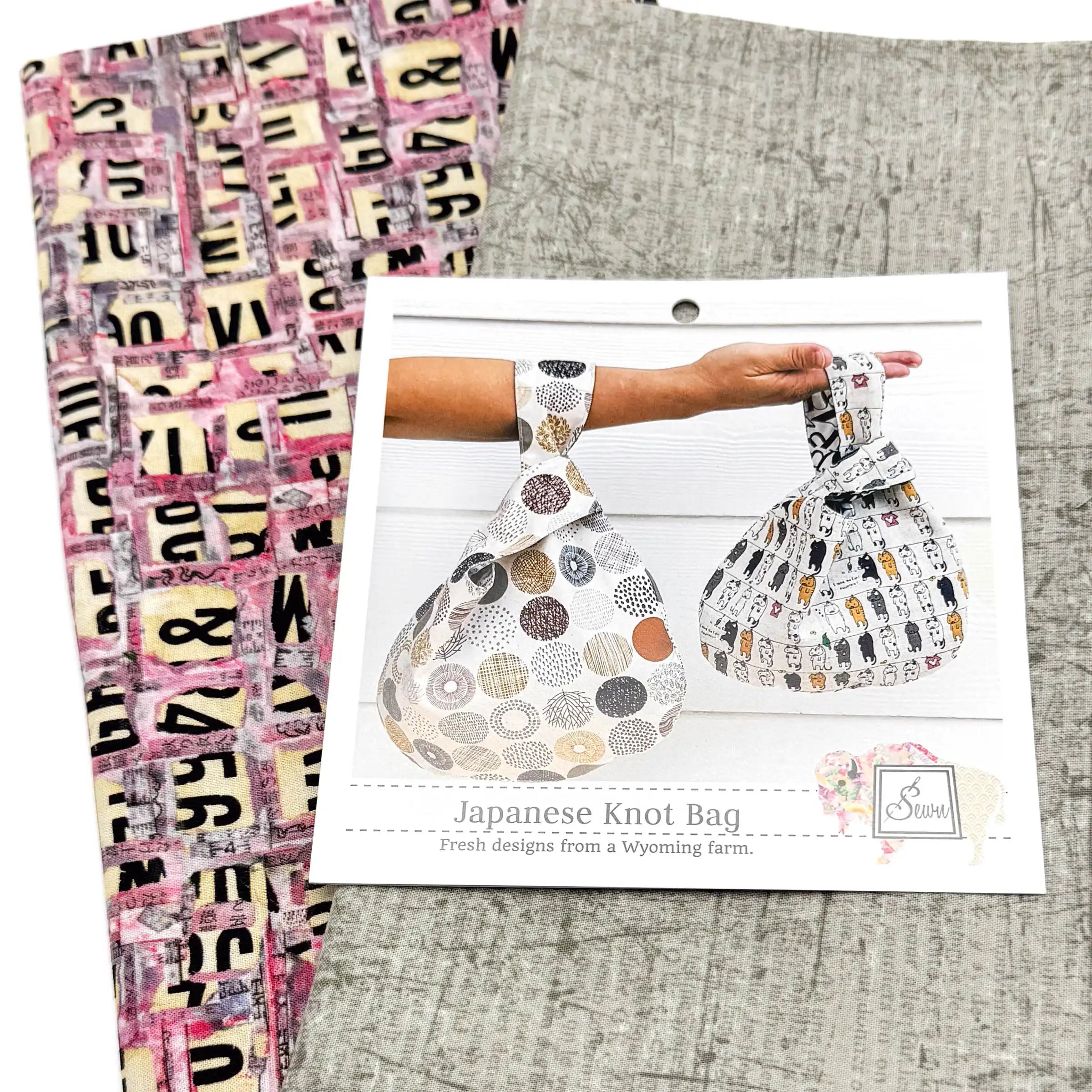 Japanese Knot Bag sewing pattern with two patterned fabrics on a textured surface