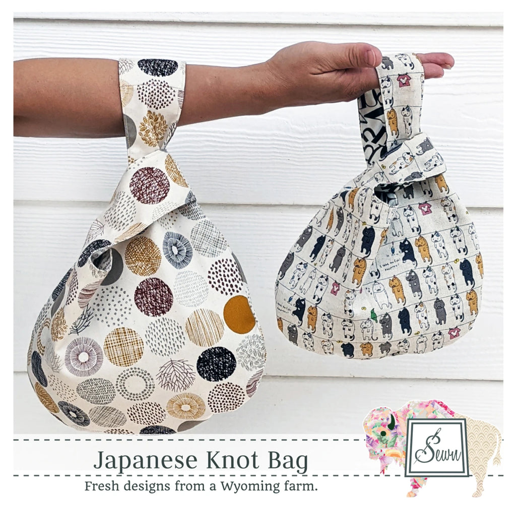 Sewing pattern cover featuring two Japanese knot bags with patterned fabric held by a hand against a white wooden background.