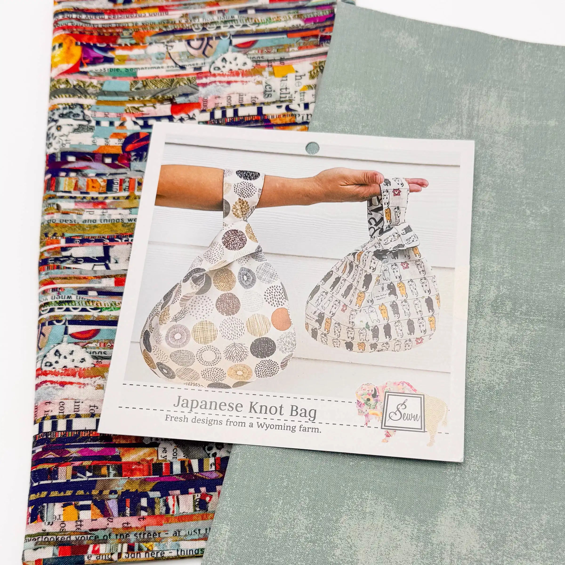 Japanese Knot Bag sewing pattern with two patterned fabrics on a white surface