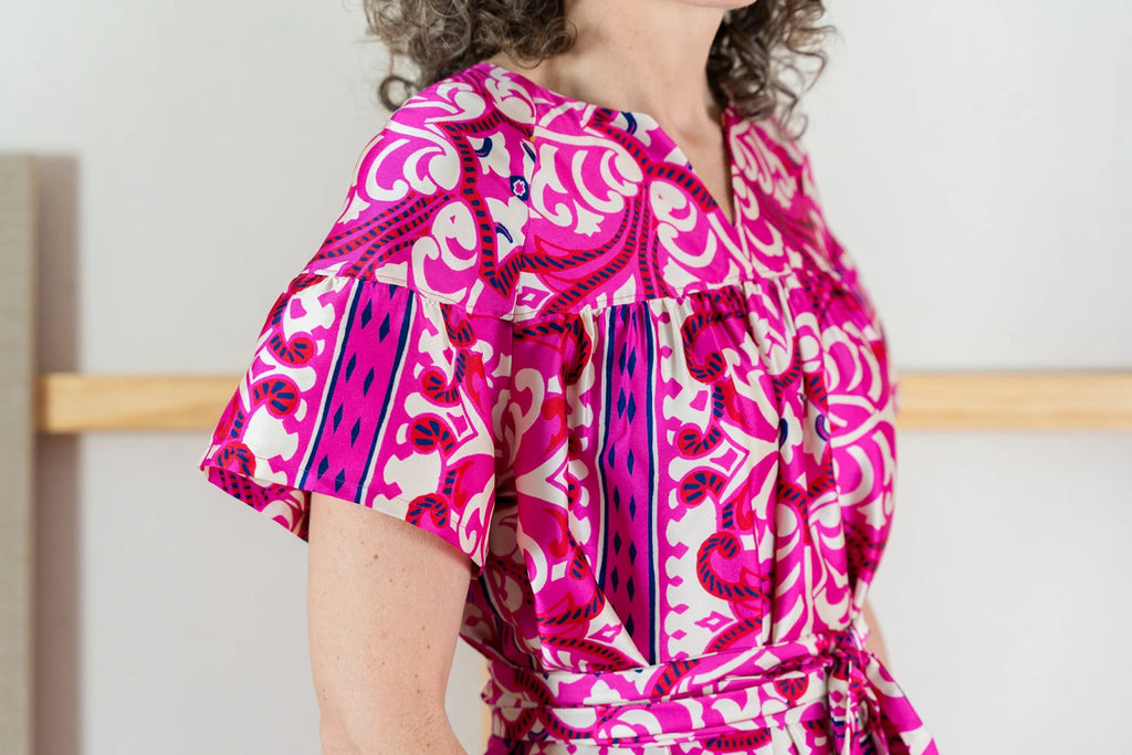 Person wearing a pink and purple patterned Positano dress with a white background