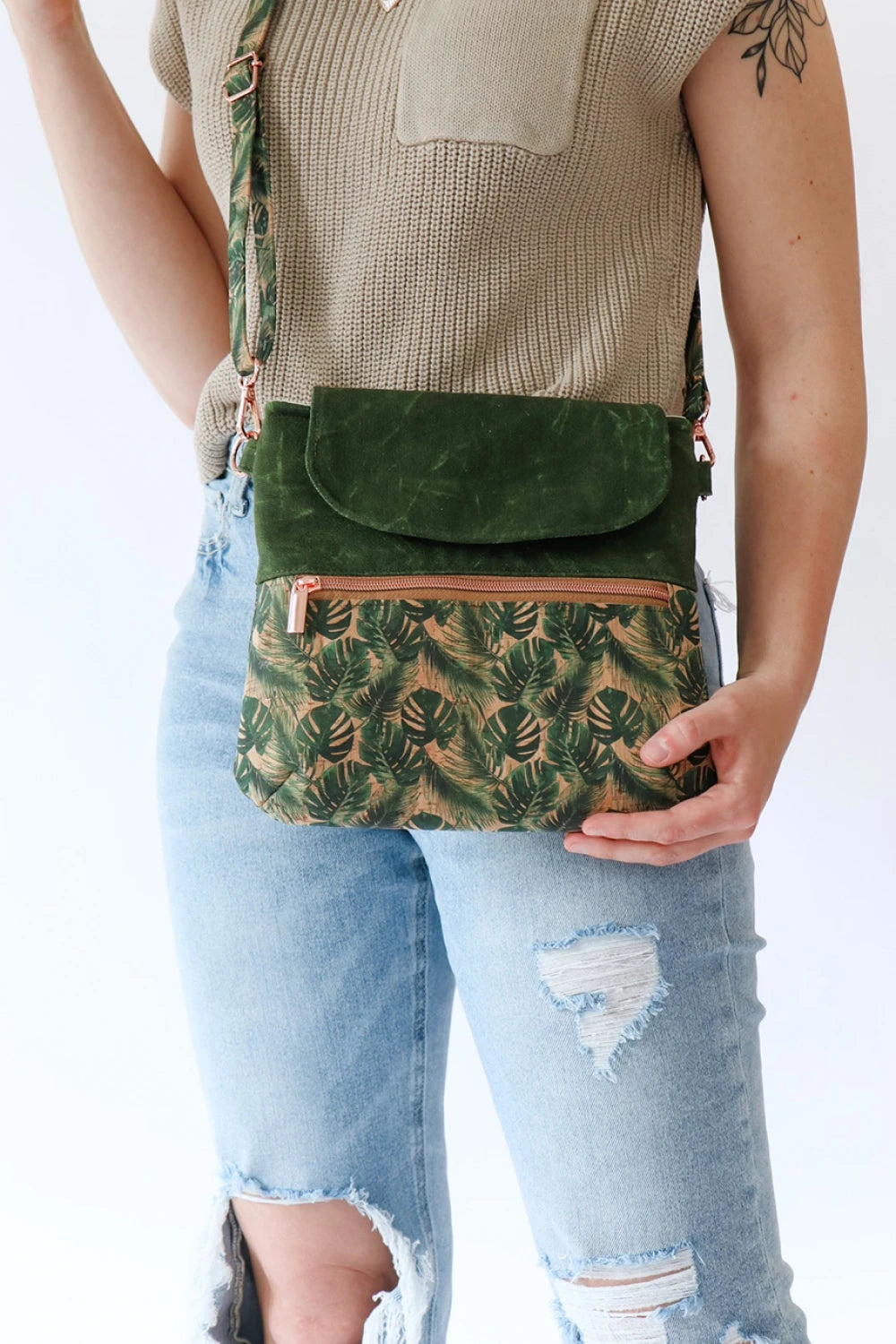 Person wearing a green crossbody bag with leaf pattern on a white background