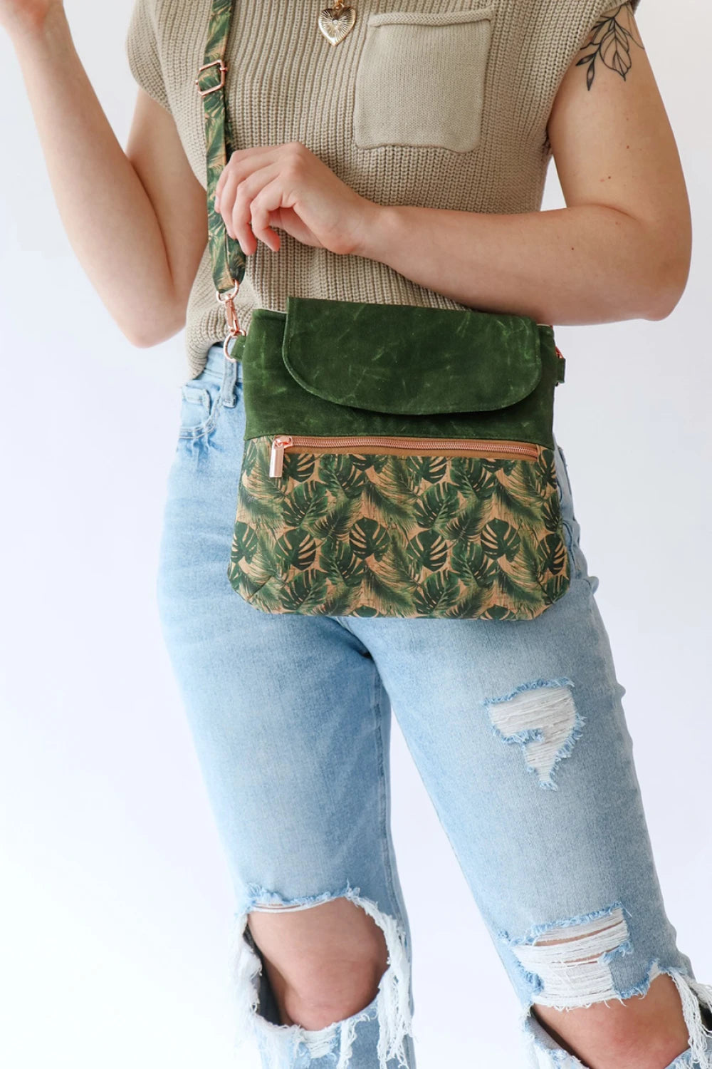 Person wearing a green patterned crossbody bag with a plain background