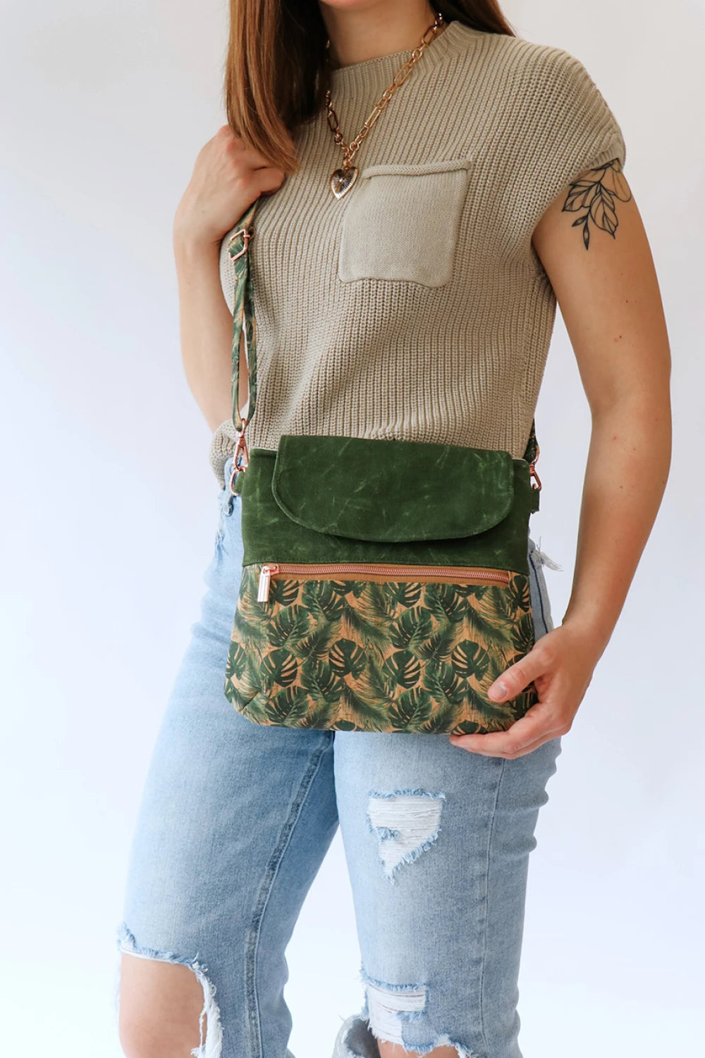 Person wearing a green patterned crossbody bag with a plain background
