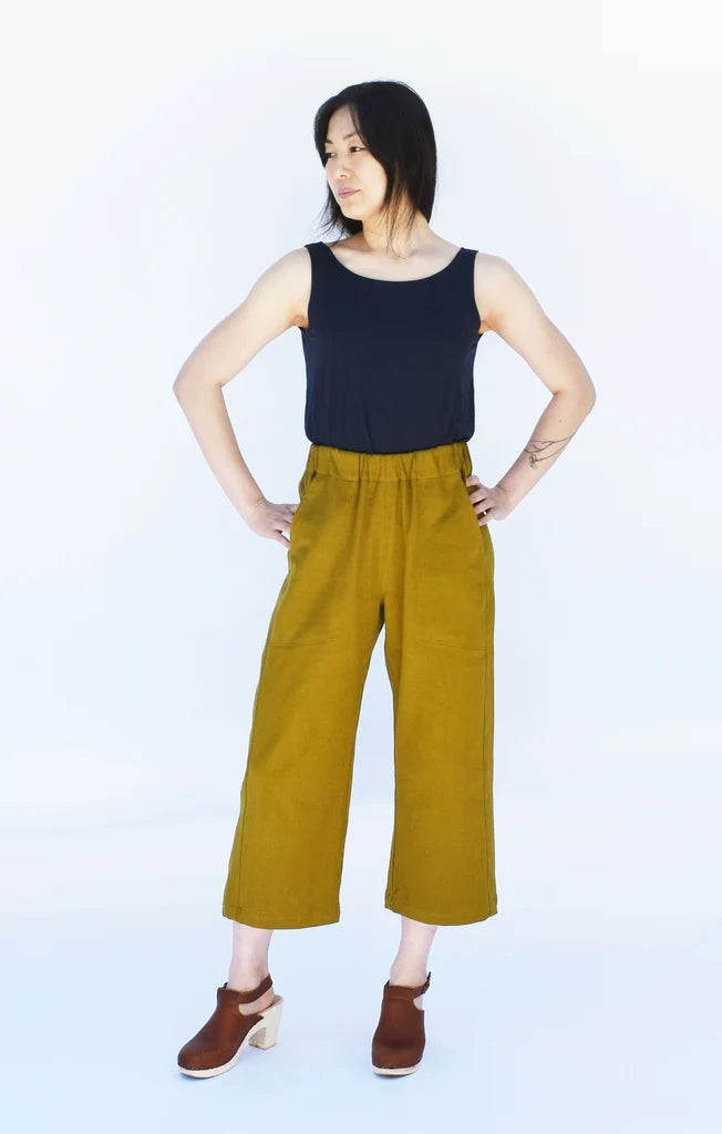 Woman wearing cropped mustard yellow Free Range Slacks and a black top on a white background