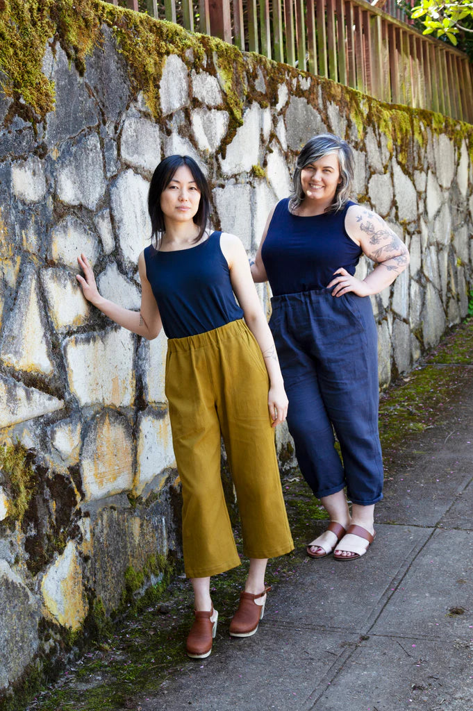 Two women standing against a stone wall, wearing matching outfits with Sew House Seven Free Range Slacks.