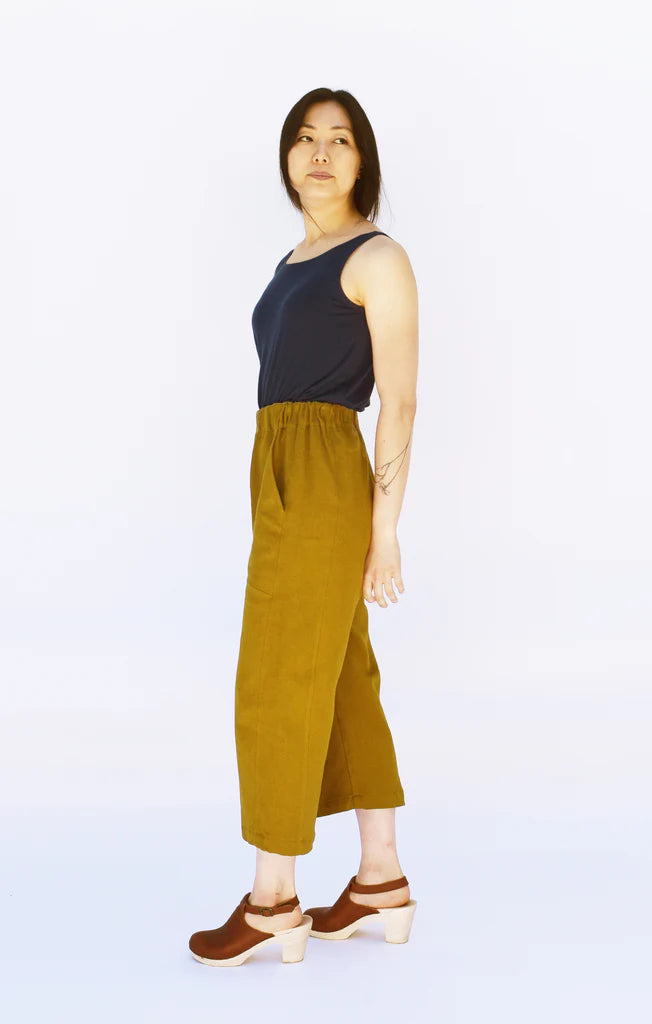 Woman wearing a navy top and cropped mustard yellow Free Range Slacks on a white background