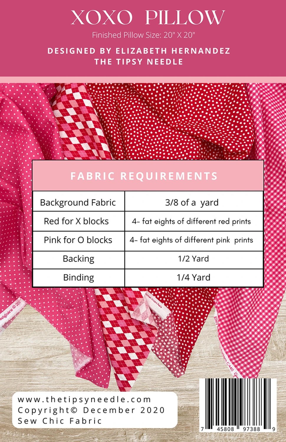 Back of sewing pattern for XOXO Pillow with pink and red patterns and fabric requirements on a wooden surface.