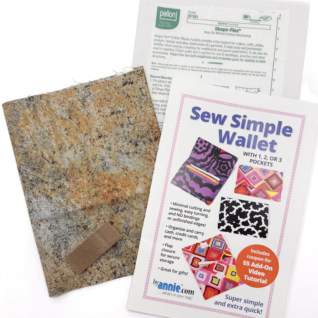 Project kit for making fabric wallet with pattern and brown fabric and interfacing on a white background